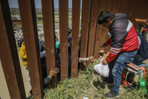 Repartidores llevan comida a migrantes hasta el muro fronterizo
