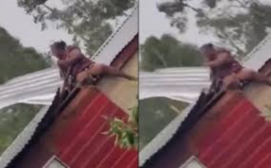Captan a mujer sujetando el techo de su casa para evitar que Beryl lo destruya
